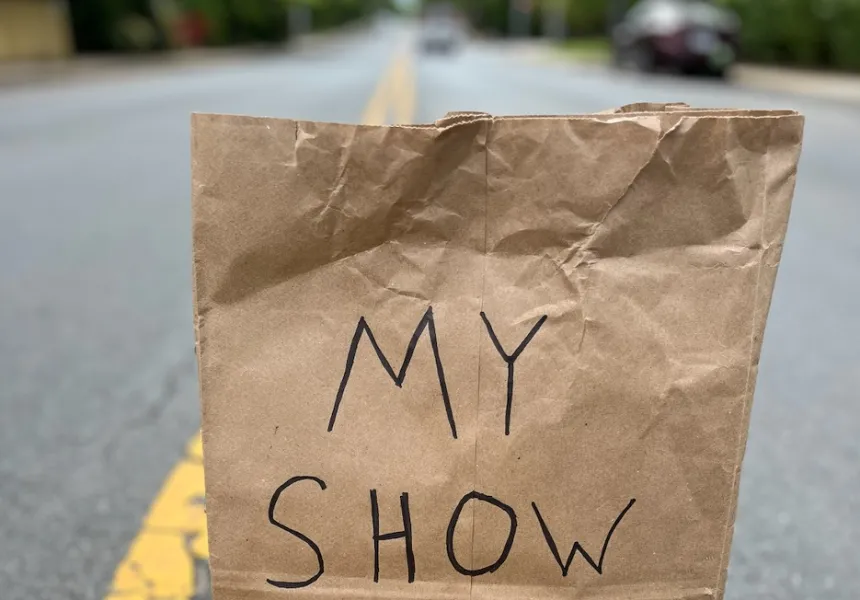 a brown paper bag labelled "My Show" sits on the yellow lines in the middle of a street