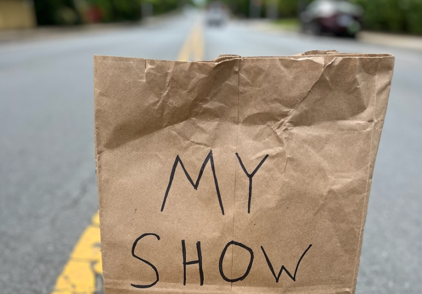a brown paper bag labelled "My Show" sits on the yellow lines in the middle of a street