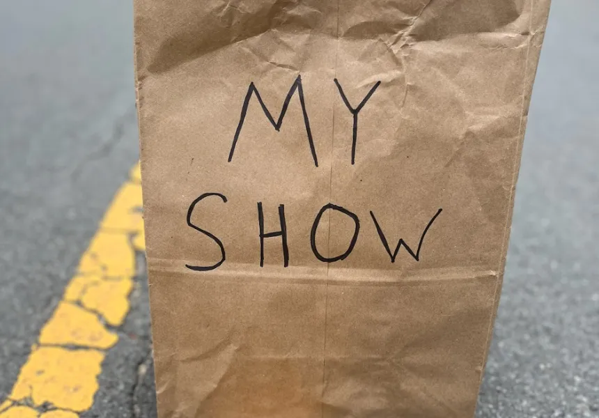 Brown paper bag labelled "My Show" sits on yellow lines in a street