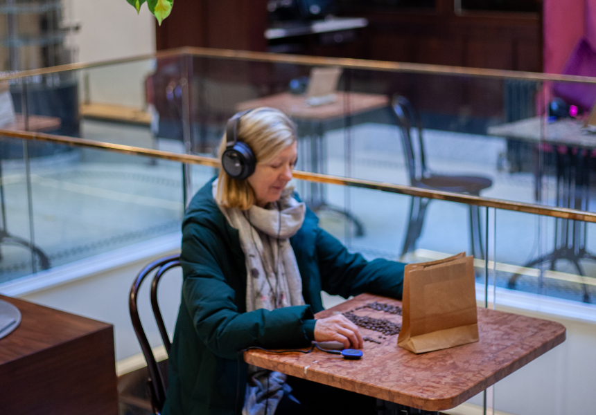 A woman sitting in a coffee shop with headphones on