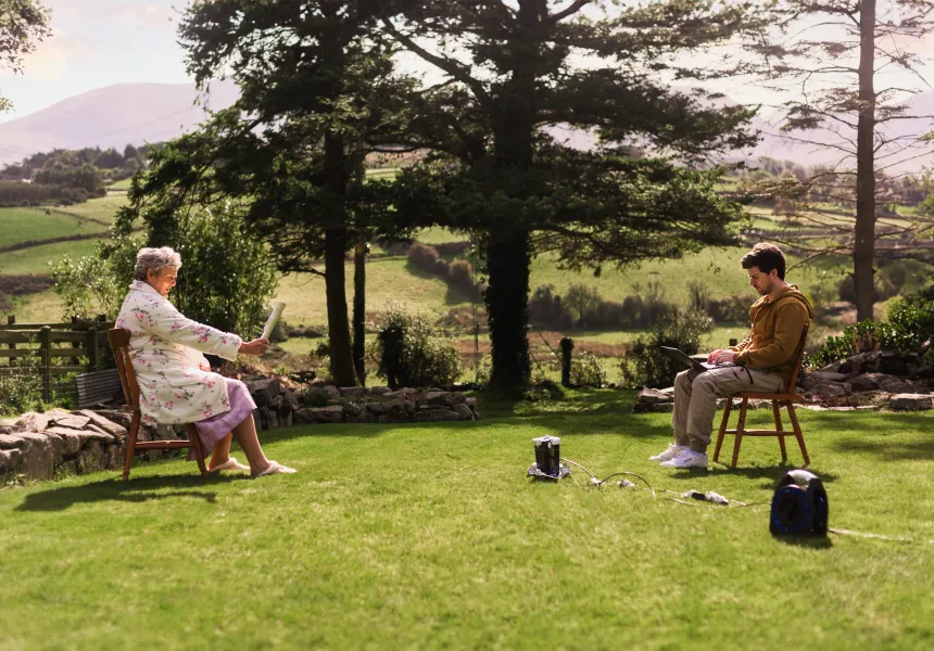 DEAR IMELDA image, young man and older woman sitting on the lawn